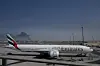 Et Emirates-fly på flyplassen i Dubai med røyk fra et iransk angrep i bakgrunnen.