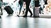 Reisende med bagasje og trillekofferter i en flyplassterminal.