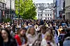 Mange mennesker går langs Karl Johans gate i Oslo med bygninger og butikker på begge sider.
