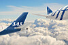 To SAS-fly over et hvitt skylag under blå himmel.