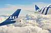 To SAS-fly over et hvitt skylag under blå himmel.