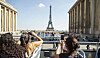 Turister på en terrasse med utsikt mot Eiffeltårnet i Paris.
