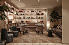 Moderne lounge med lenestoler, sofa, bokhyller og myk belysning i varme toner.