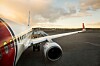 Parkert passasjerfly sett fra siden på flyplassens rullebane ved solnedgang.