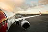 Parkert passasjerfly sett fra siden på flyplassens rullebane ved solnedgang.
