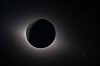 Mørk måneskive foran solen med en svak lysglorie i verdensrommet.