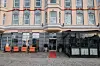 Historisk byfasade med kafébord, stoler og rød løper ved inngangen.