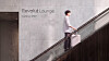 Reisende med koffert i rulletrapp foran et skilt for Revolut Lounge.