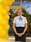 Ansatt står foran en glassinngang med en dekorasjon av gule ballonger.