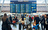 Travel flyplassterminal med reisende, bagasje og store skjermer for innsjekking.