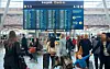 Travel flyplassterminal med reisende, bagasje og store skjermer for innsjekking.