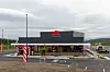 Eksteriøret av en MAX-restaurant med parkeringsplass og innkjøring.