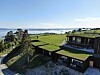 Moderne bygg med grønne tak i et åpent kystlandskap ved fjorden.
