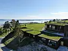 Moderne bygg med grønne tak i et åpent kystlandskap ved fjorden.