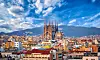 Panoramautsikt over Barcelona med Sagrada Família sentralt i bybildet og fjell i bakgrunnen.