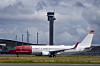 Norwegian-fly på bakken ved Gardermoen med flytårnet og skyer i bakgrunnen.
