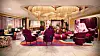 Elegant hotell-lounge med gjester i fargerike lenestoler og sofaer.