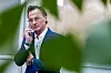 Petter A. Stordalen i dress snakker i telefonen, delvis skjult av grønne planter.
