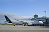 Lufthansa-fly parkert ved terminalen på München lufthavn under en klar blå himmel.