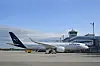 Lufthansa-fly parkert ved terminalen på München lufthavn under en klar blå himmel.
