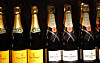 Champagneflasker fra Veuve Clicquot og Moët & Chandon på en mørk butikkhylle.
