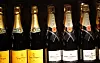 Champagneflasker fra Veuve Clicquot og Moët & Chandon på en mørk butikkhylle.