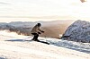 Skikjører i svart og blått utstyr på en snødekt fjellside.