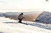 Skikjører i svart og blått utstyr på en snødekt fjellside.
