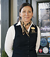 Smilende kvinne i uniform står foran en inngangsdør med plakater og klistremerker.