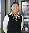 Smilende kvinne i uniform står foran en inngangsdør med plakater og klistremerker.