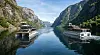 To båter på en speilblank fjord omgitt av høye, grønne fjell.