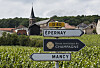 Veiskilt mot Épernay og Mancy foran vinmarker og en kirke i Champagne-regionen.