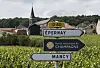 Veiskilt mot Épernay og Mancy foran vinmarker og en kirke i Champagne-regionen.